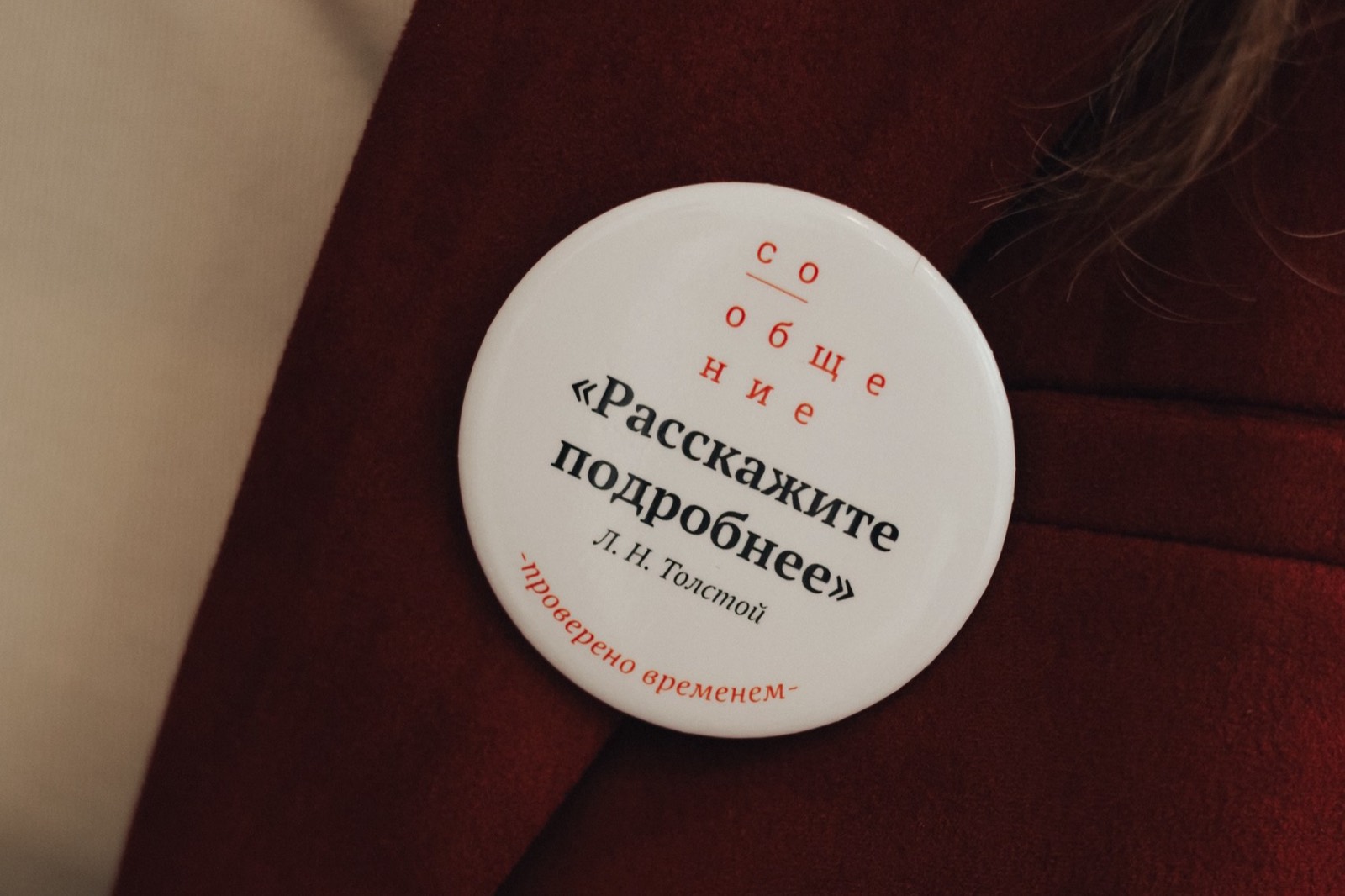 Значок школы «СоОбщение» с надписью «Расскажите подробнее» на бордовом пиджаке
